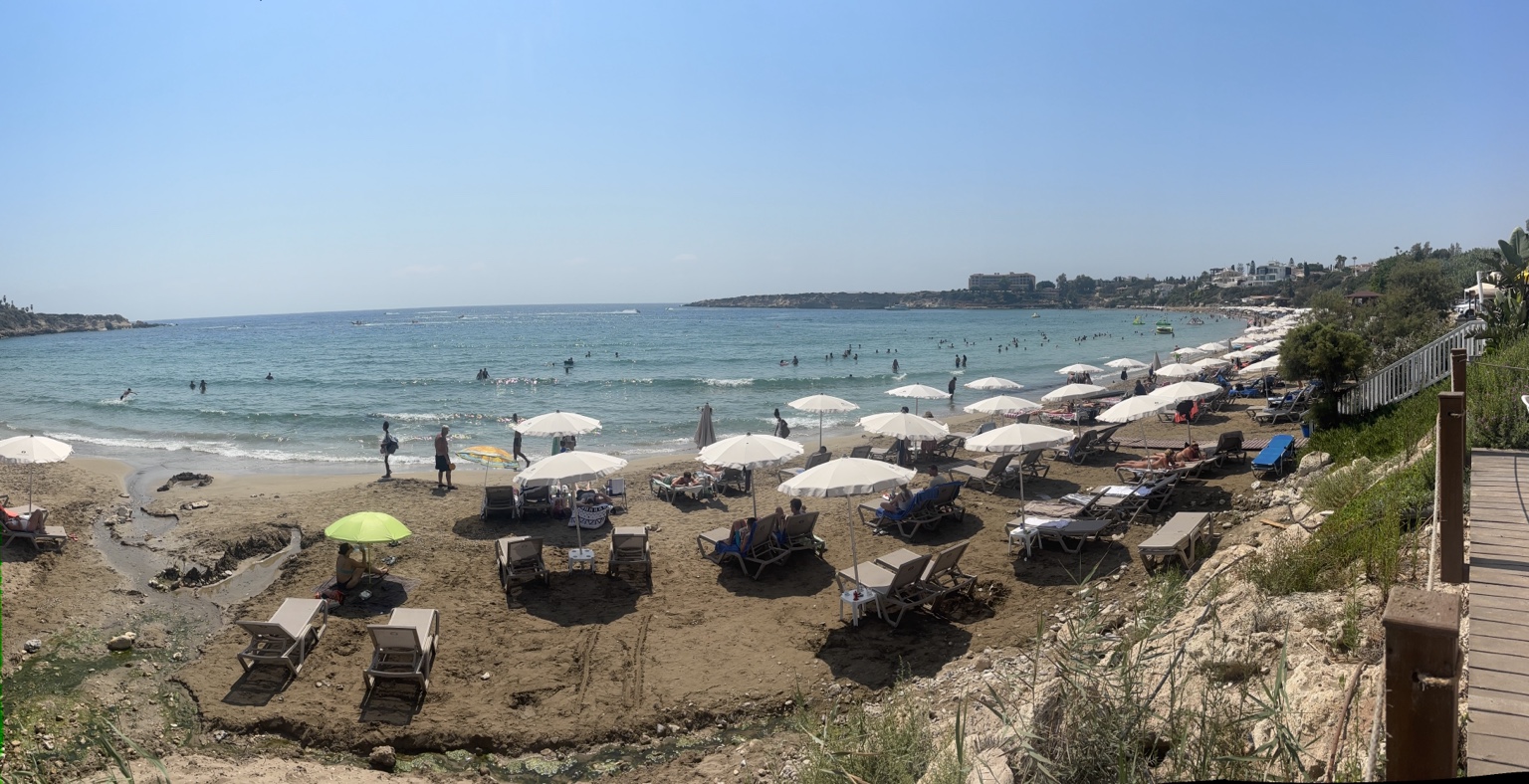 Coral Bay mit Sandstrand, Liegen und Sonnenschirmen